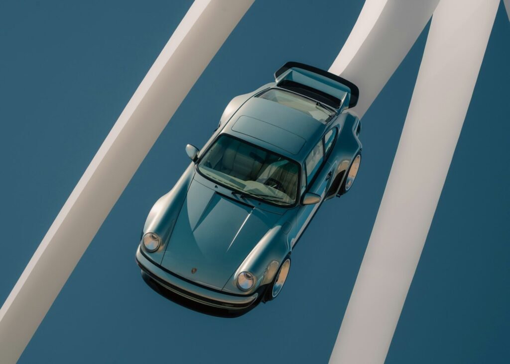 Classic light blue car suspended between white architectural beams.